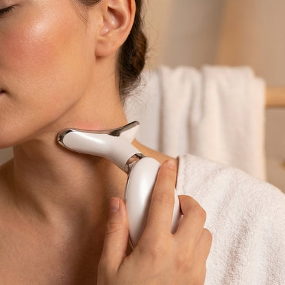 Person using a white electronic device on their neck with a towel in the background